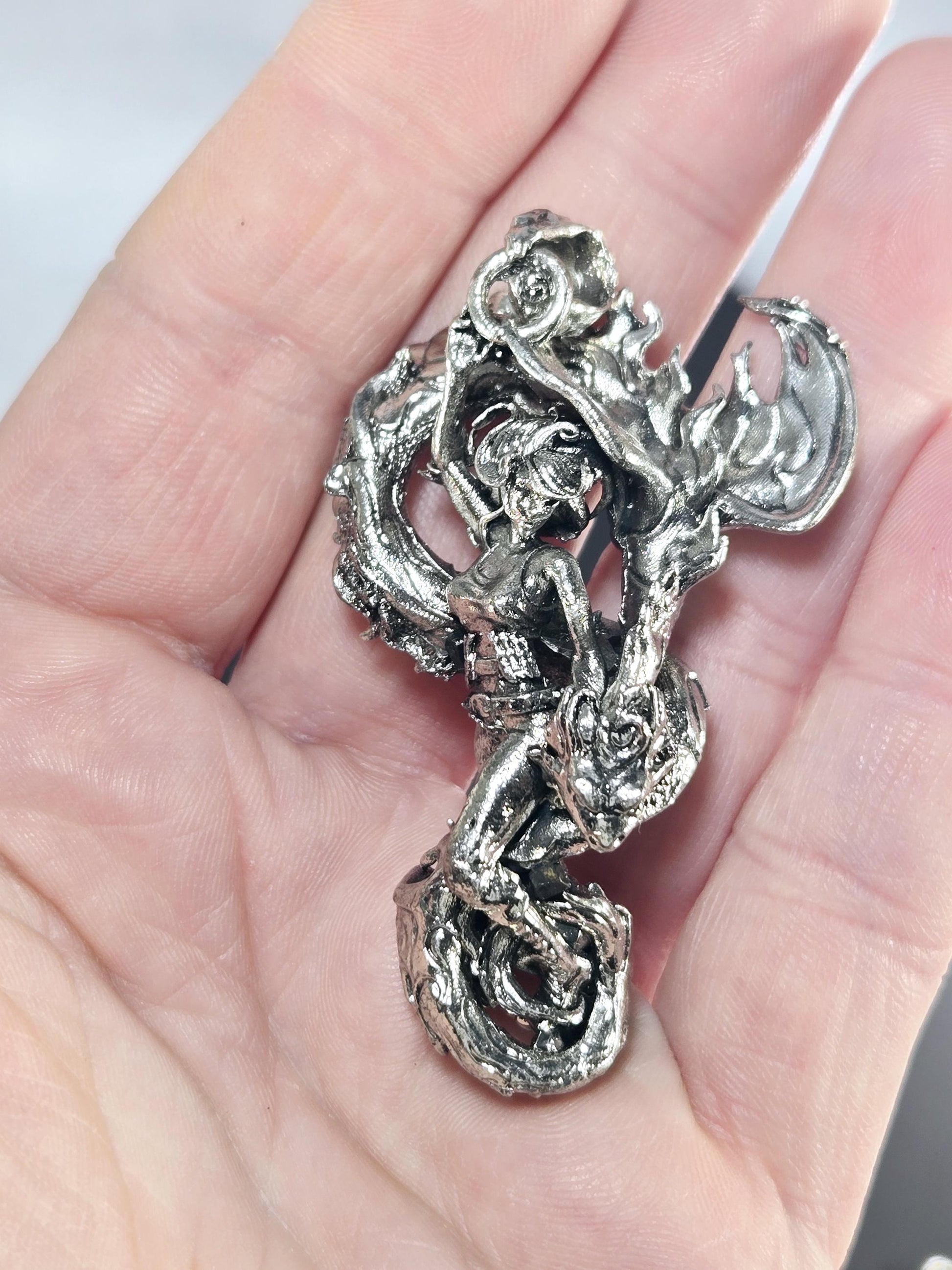 A hand holding a silver dragon figurine.