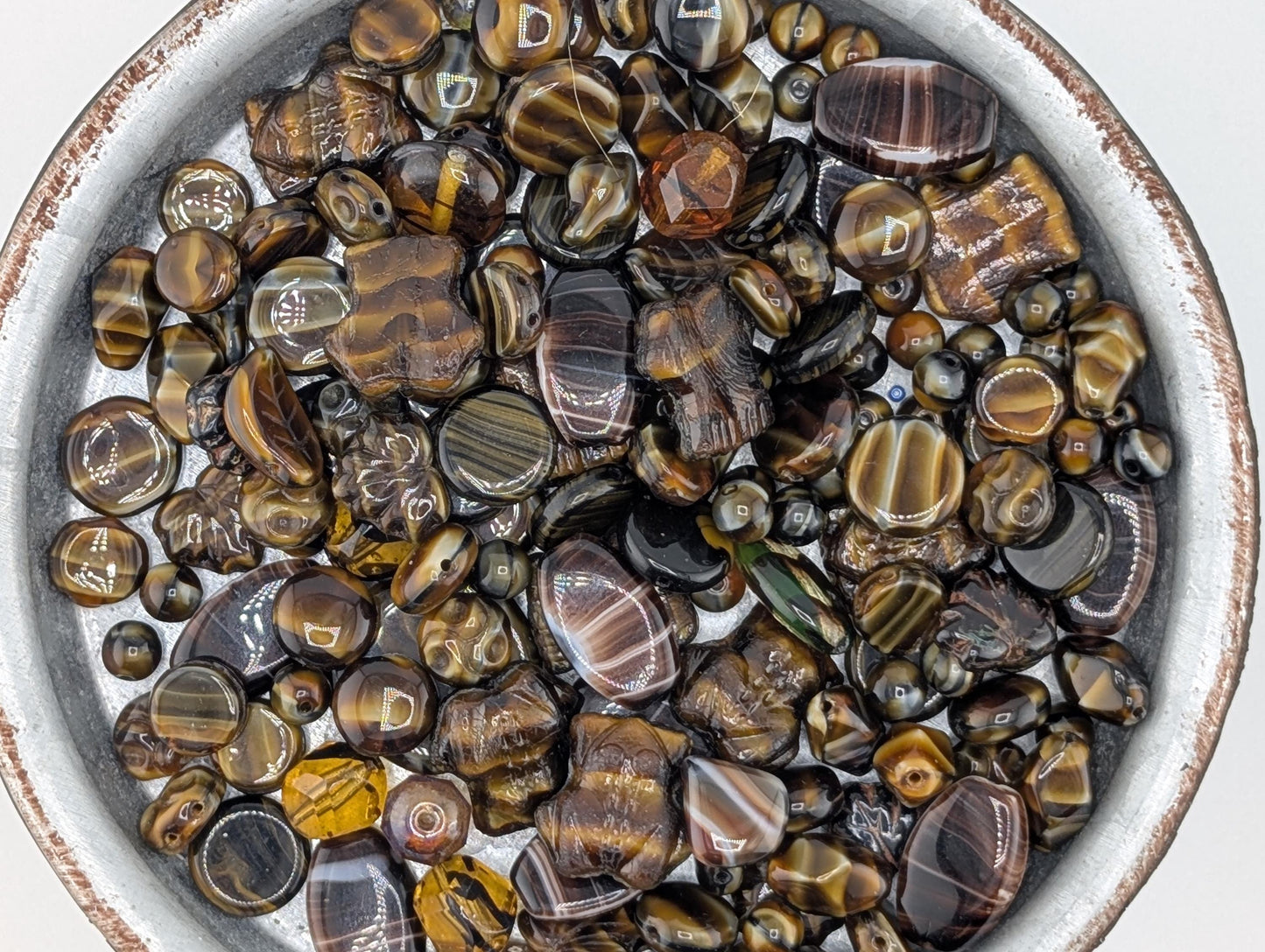 A bowl filled with various colored beads, including black, brown, and yellow, arranged in a visually appealing manner.