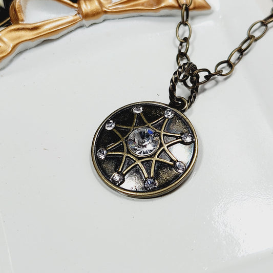 A close-up view of a decorative pendant necklace with a circular design featuring a central gemstone surrounded by smaller gemstones.