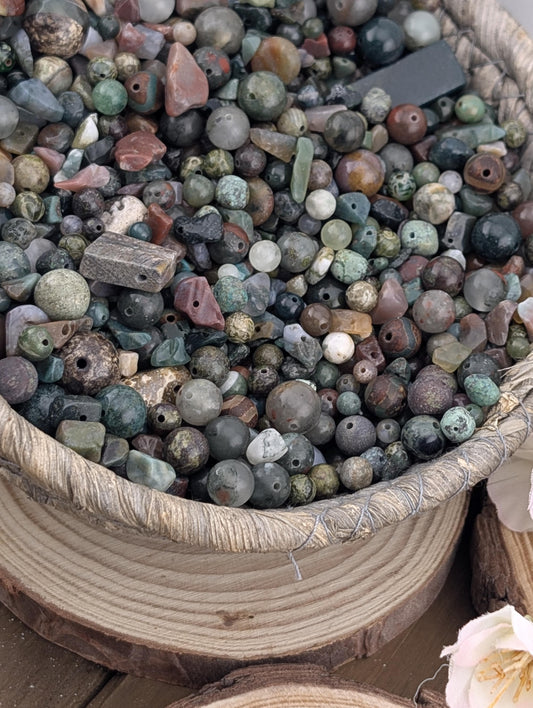 A wooden bowl filled with a variety of colorful beads, stones, and other natural materials.