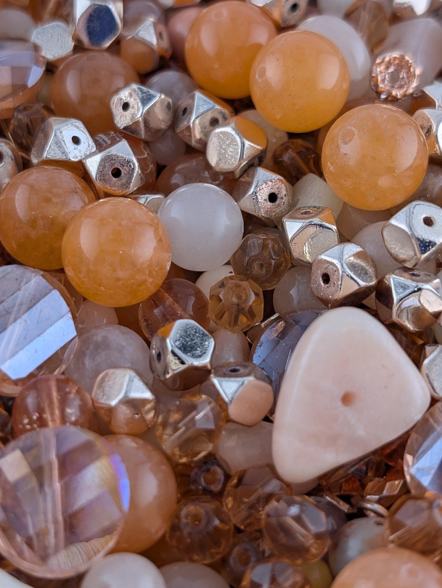 The image is a close-up of various beads and beads, including clear and multicolored glass beads, metal beads, and other small objects.