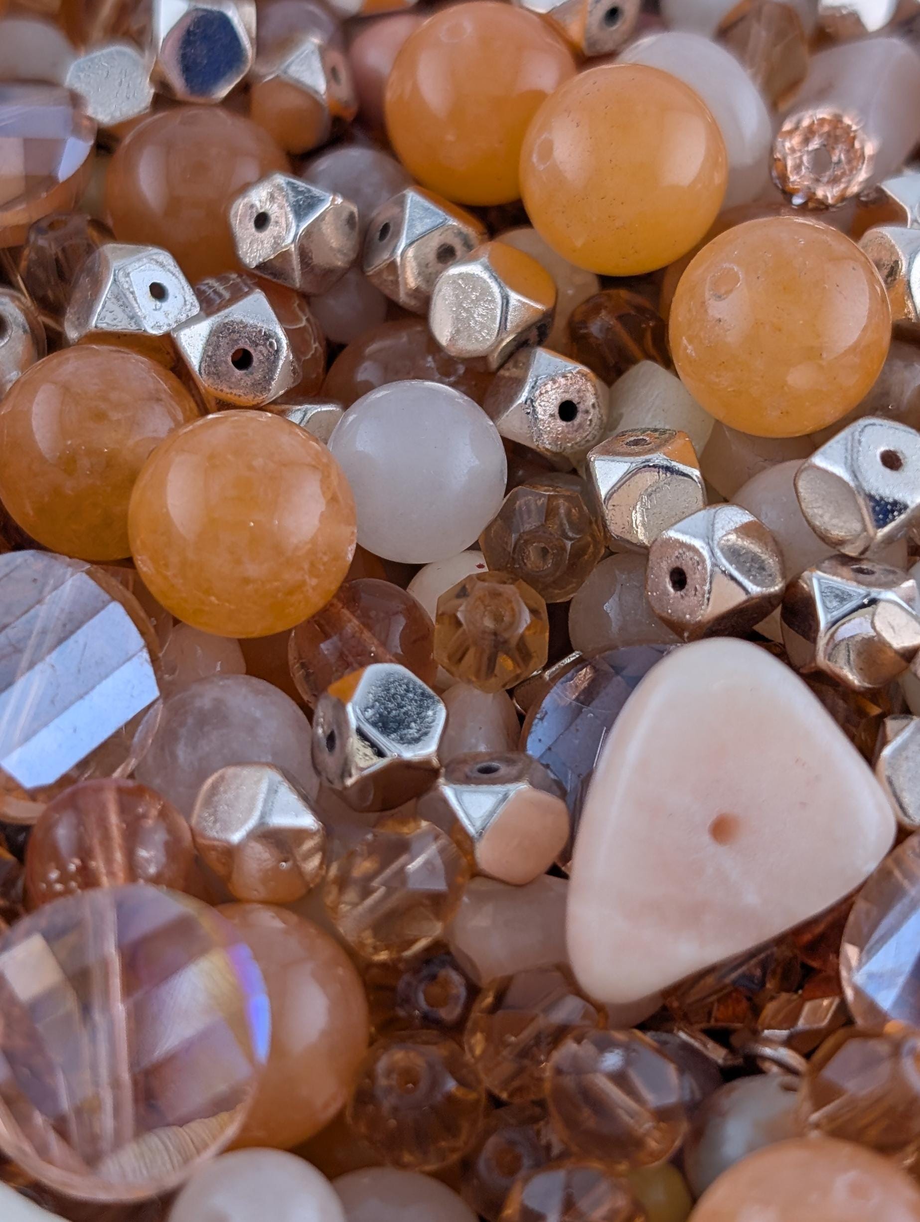 The image is a close-up of various beads and beads, including clear and multicolored glass beads, metal beads, and other small objects.