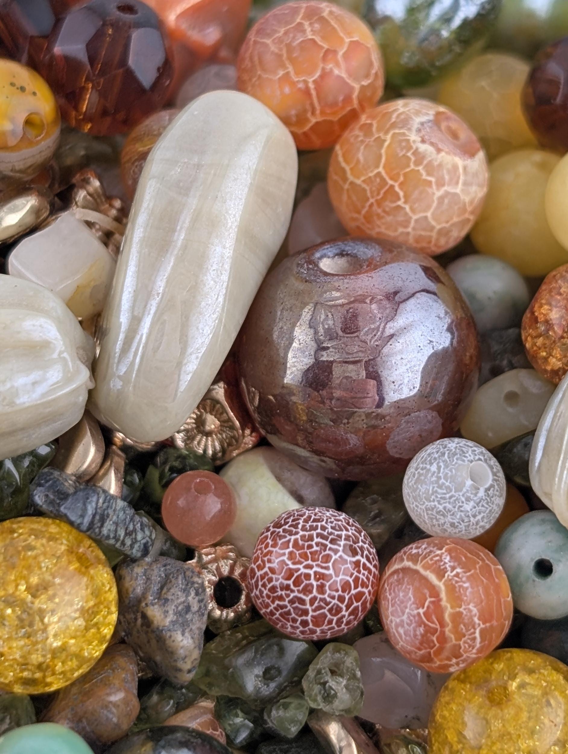 The image is a close-up of various colorful beads and stones, including glass beads, gemstones, and other natural materials.