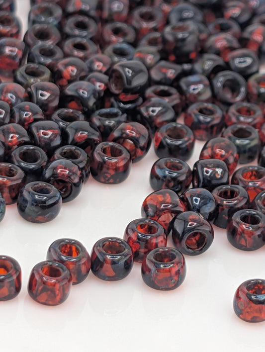 a collection of red and black beads scattered across a white surface.