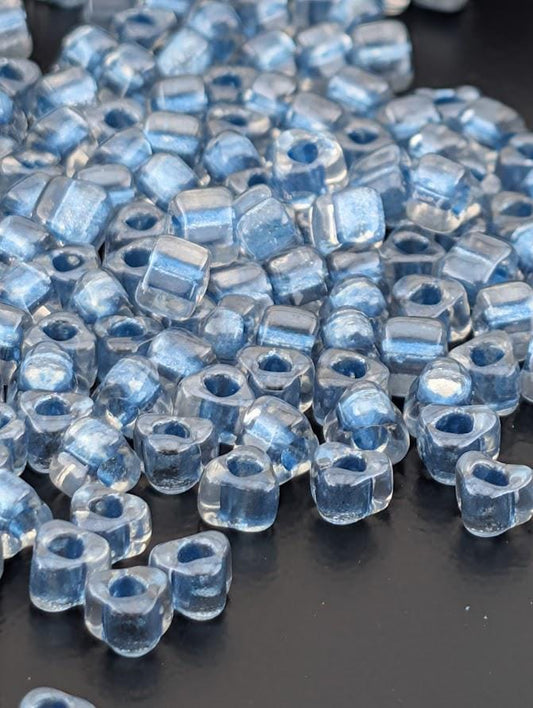 a close-up view of numerous clear glass beads scattered on a dark surface.