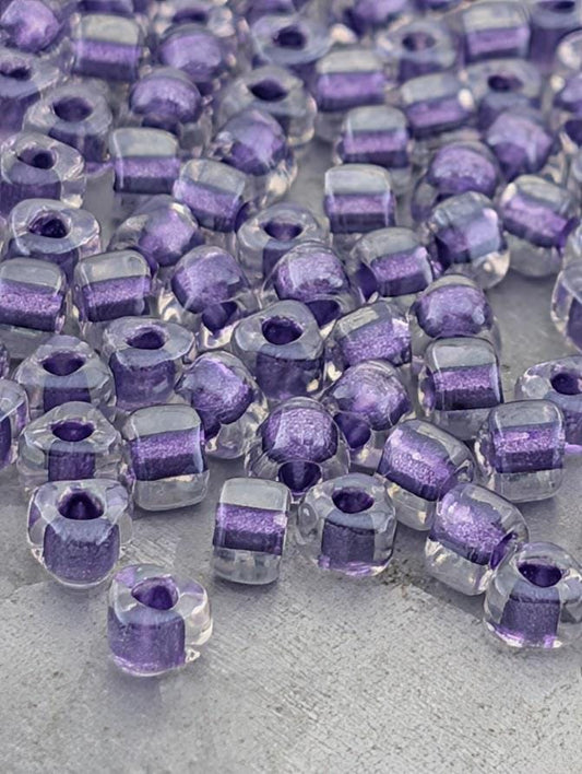 a collection of clear glass beads in various shades of purple, scattered across a surface.