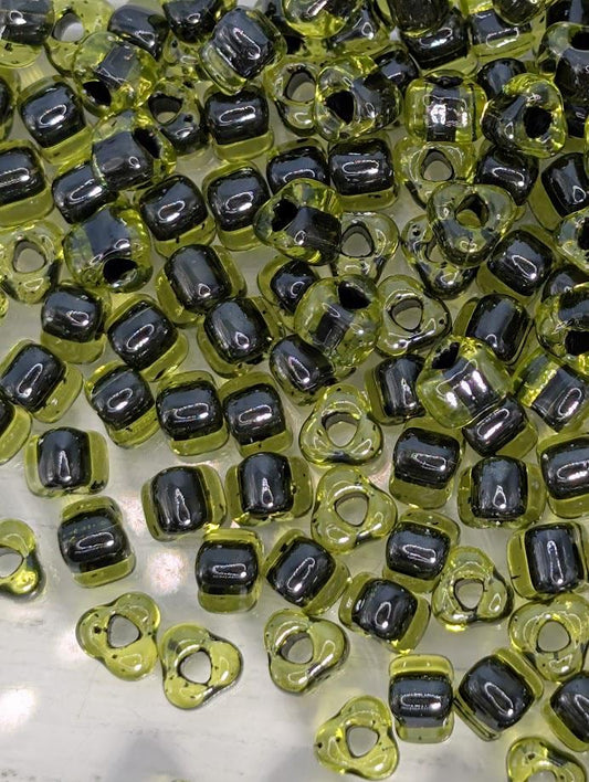 a collection of small, clear beads in various shades of green and black, scattered across a surface.