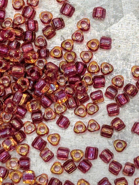 a collection of small, colorful beads scattered across a surface, with a variety of colors including shades of pink, orange, and yellow.