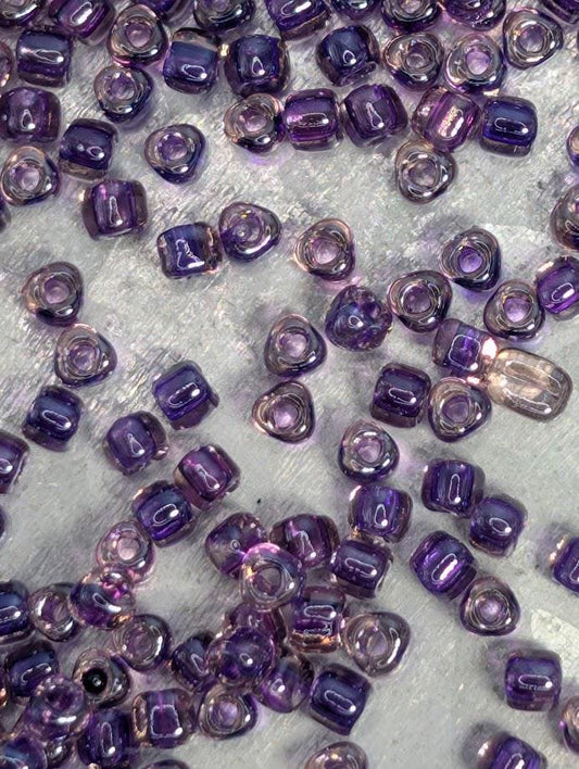 a collection of small, clear beads in various shades of purple, scattered across a surface.