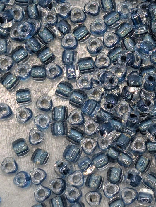 a collection of small, clear beads in various shades of blue and silver, scattered across a surface.