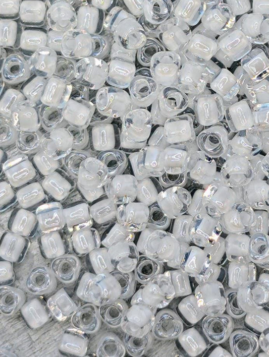 The image is a close-up of numerous clear glass beads scattered across a surface.