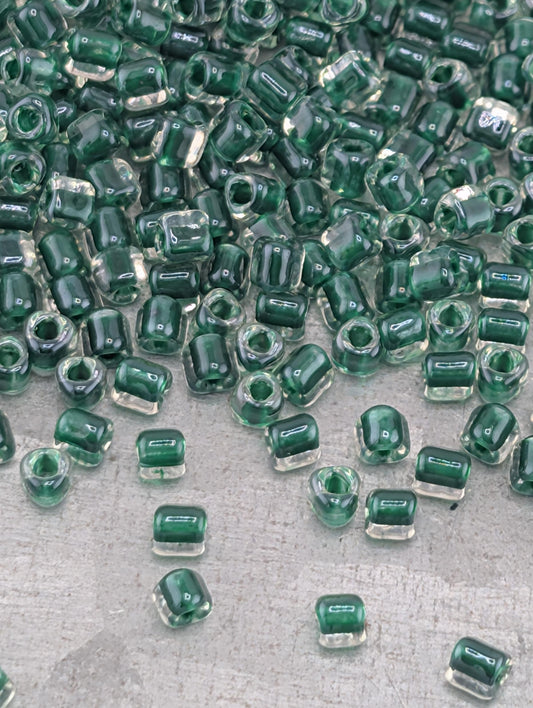 a collection of green glass beads scattered on a surface, with some of the beads overlapping each other.