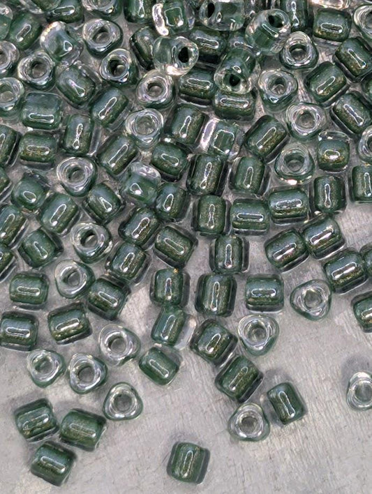 a collection of green glass beads scattered on a surface, with some of the beads overlapping each other.