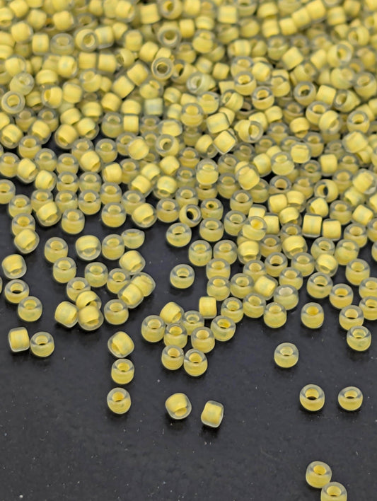 a large pile of yellow beads scattered on a dark surface.