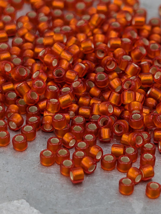 a large pile of small, round, orange beads scattered on a surface.