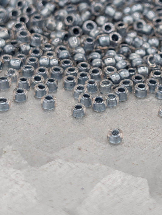 a close-up view of numerous small metal nuts or bolts scattered across a surface, with some of them appearing to be wet.