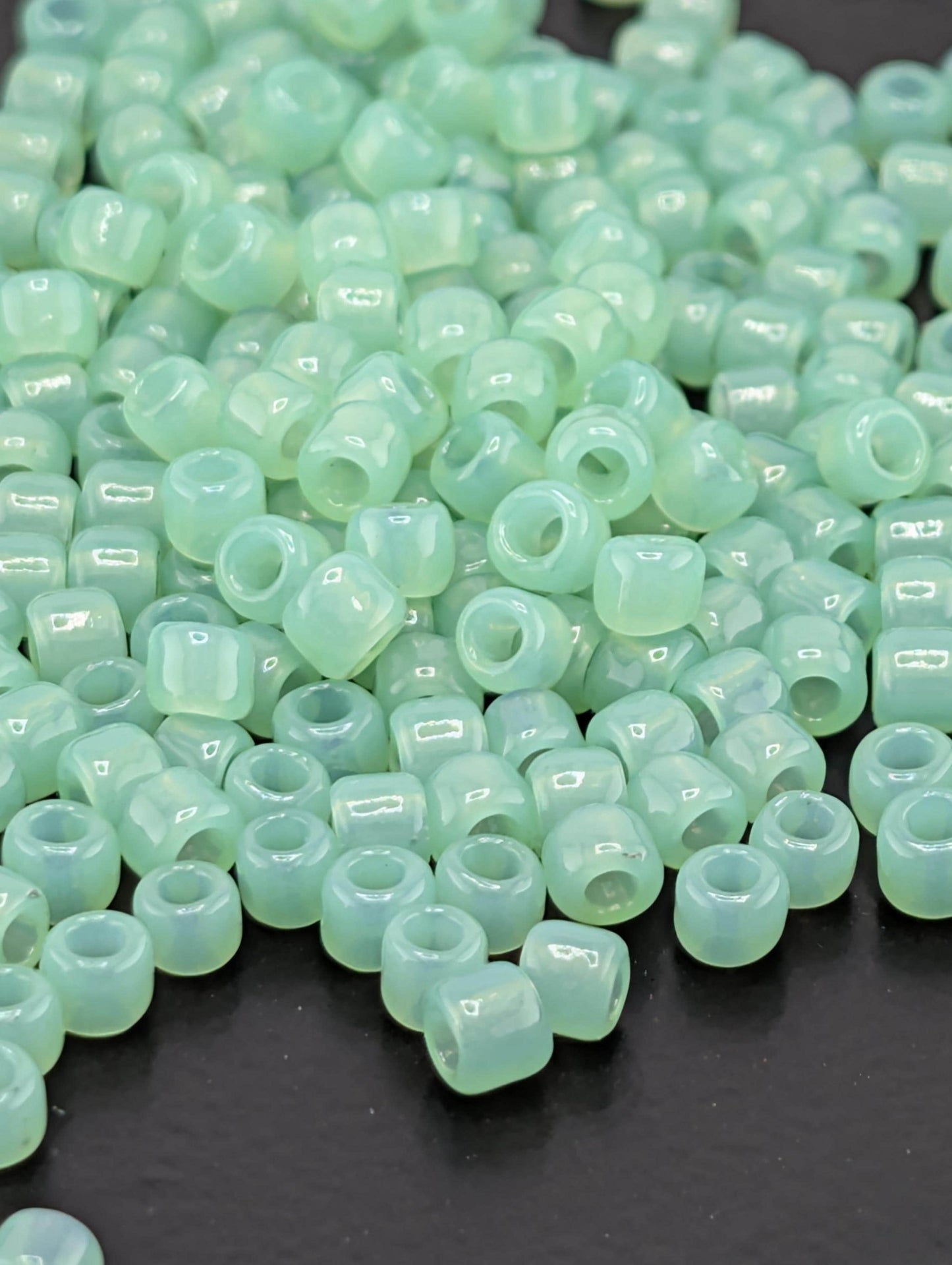 a collection of small, round, green beads scattered on a dark surface.