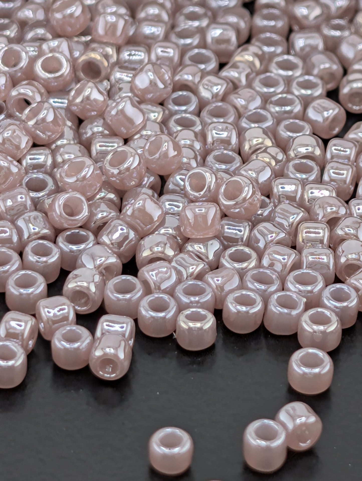 a large pile of small, round, and shiny beads scattered on a dark surface.