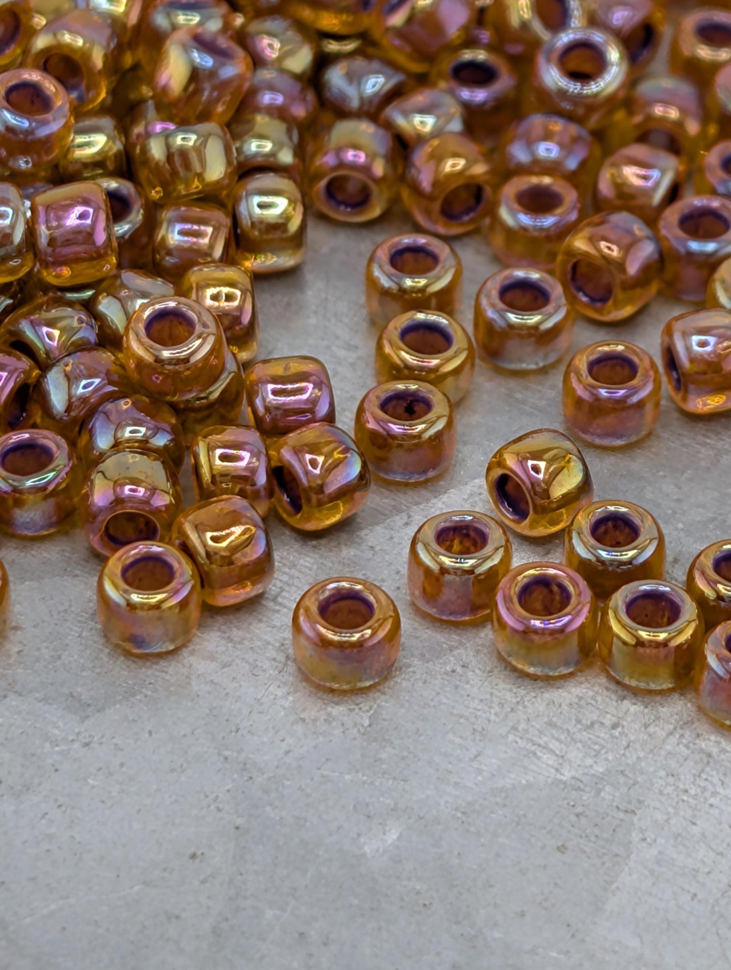 a collection of small, round beads in various colors, including gold, purple, and orange, scattered on a surface.