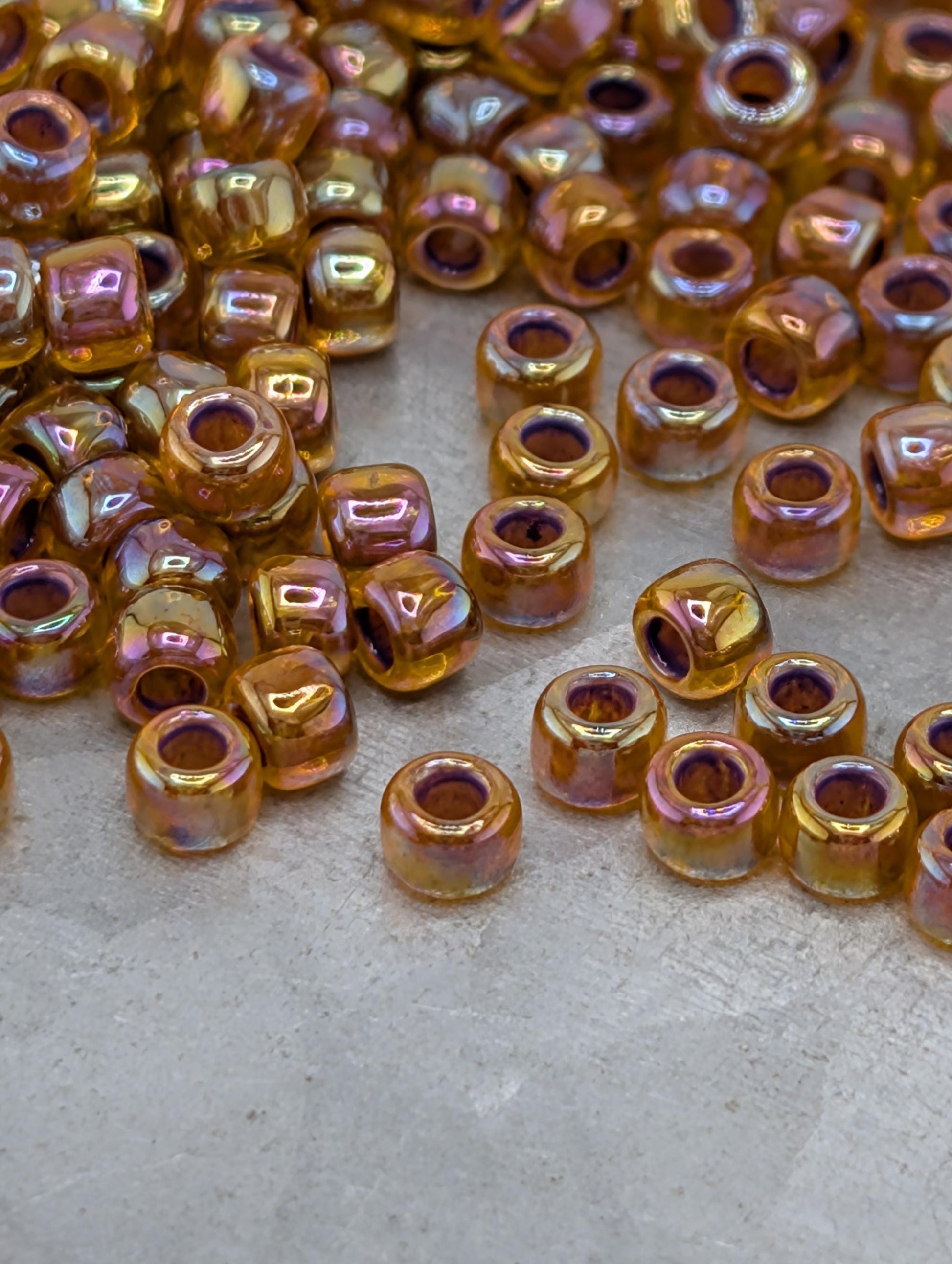 a collection of small, round beads in various colors, including gold, purple, and orange, scattered on a surface.