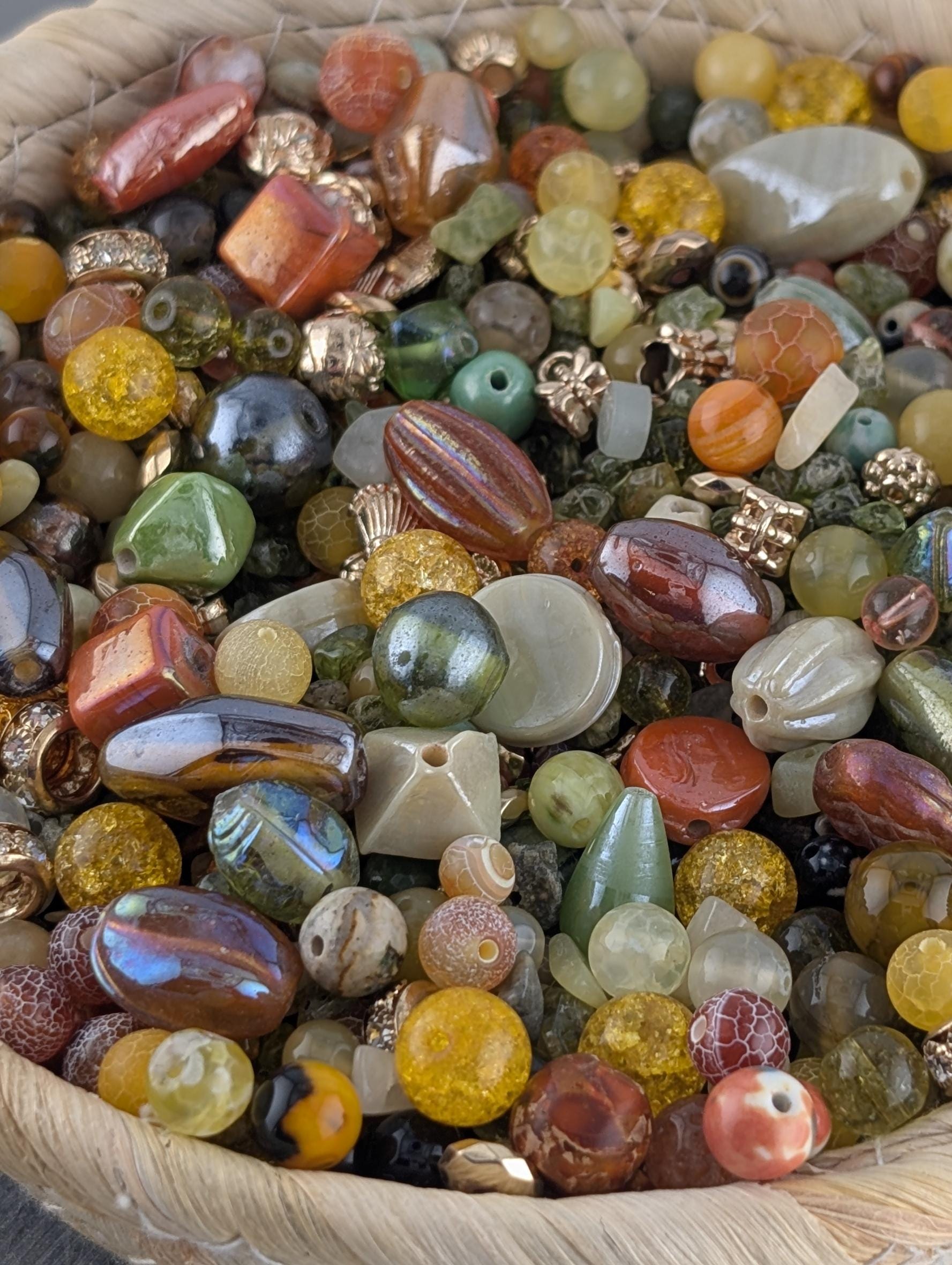 A basket filled with a variety of colorful beads, including glass, metal, and stone beads in shades of red, orange, yellow, green, blue, and purple.