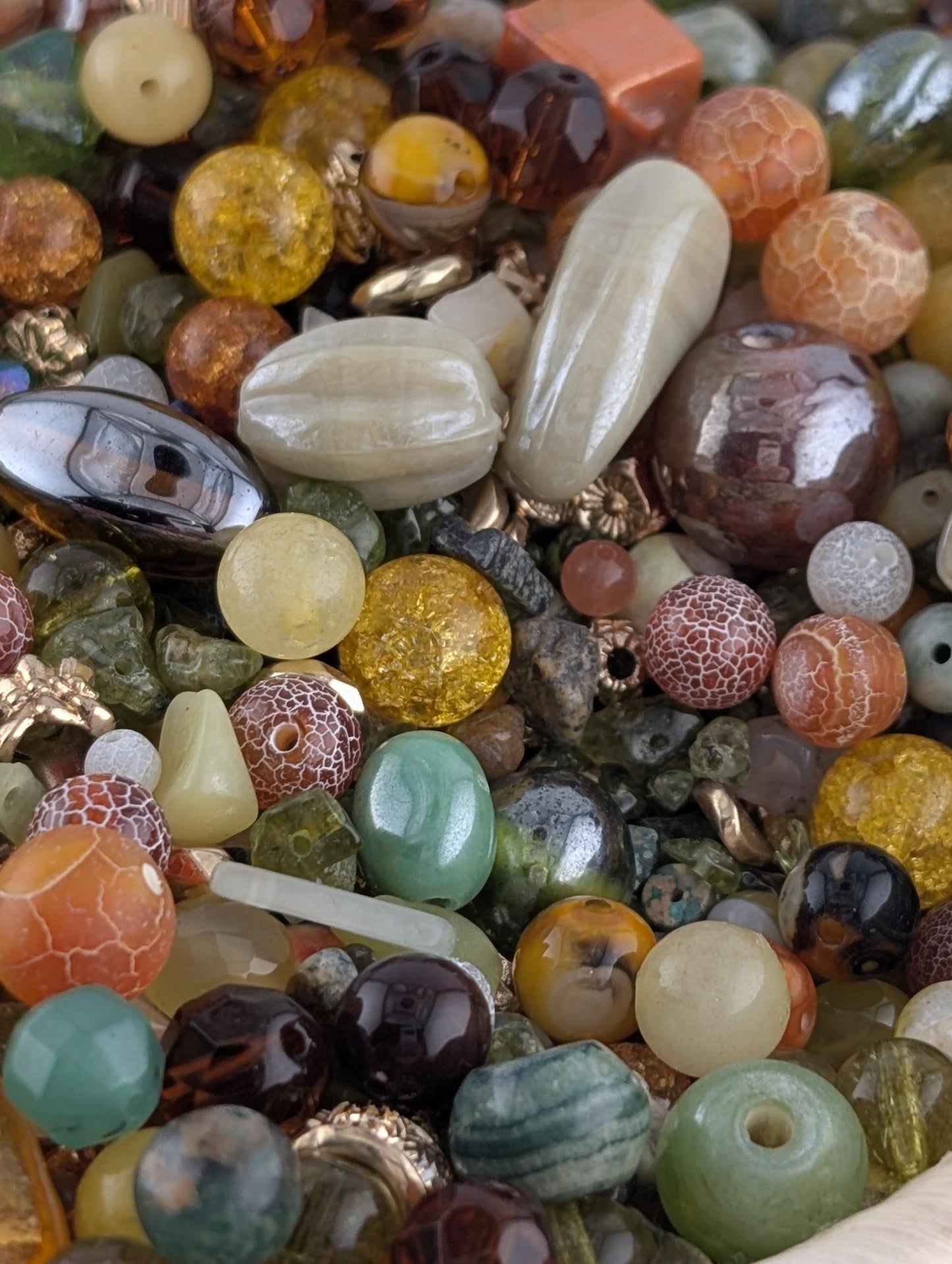 The image is a close-up of a variety of colorful beads and gemstones, including glass beads, metal beads, and natural stones, arranged in a visually appealing manner.