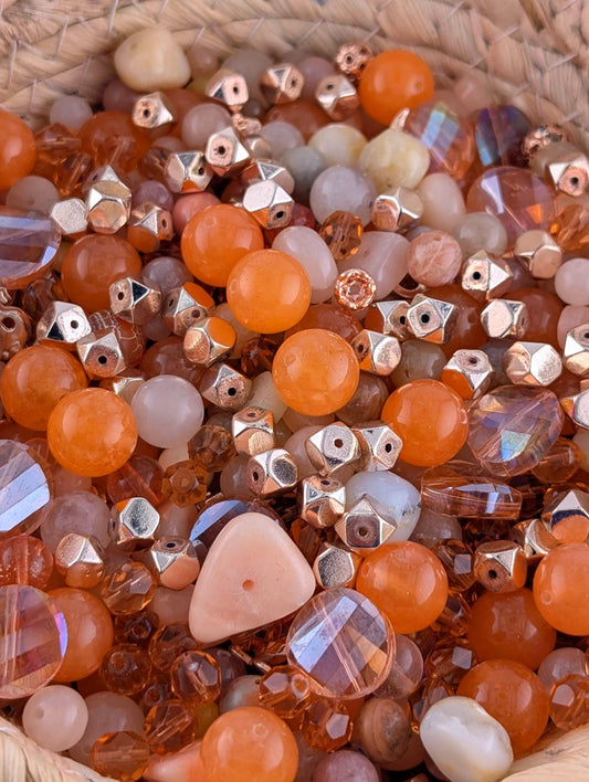 a close-up view of a collection of various beads and glass beads, including clear, white, and multicolored glass beads, as well as metal beads.