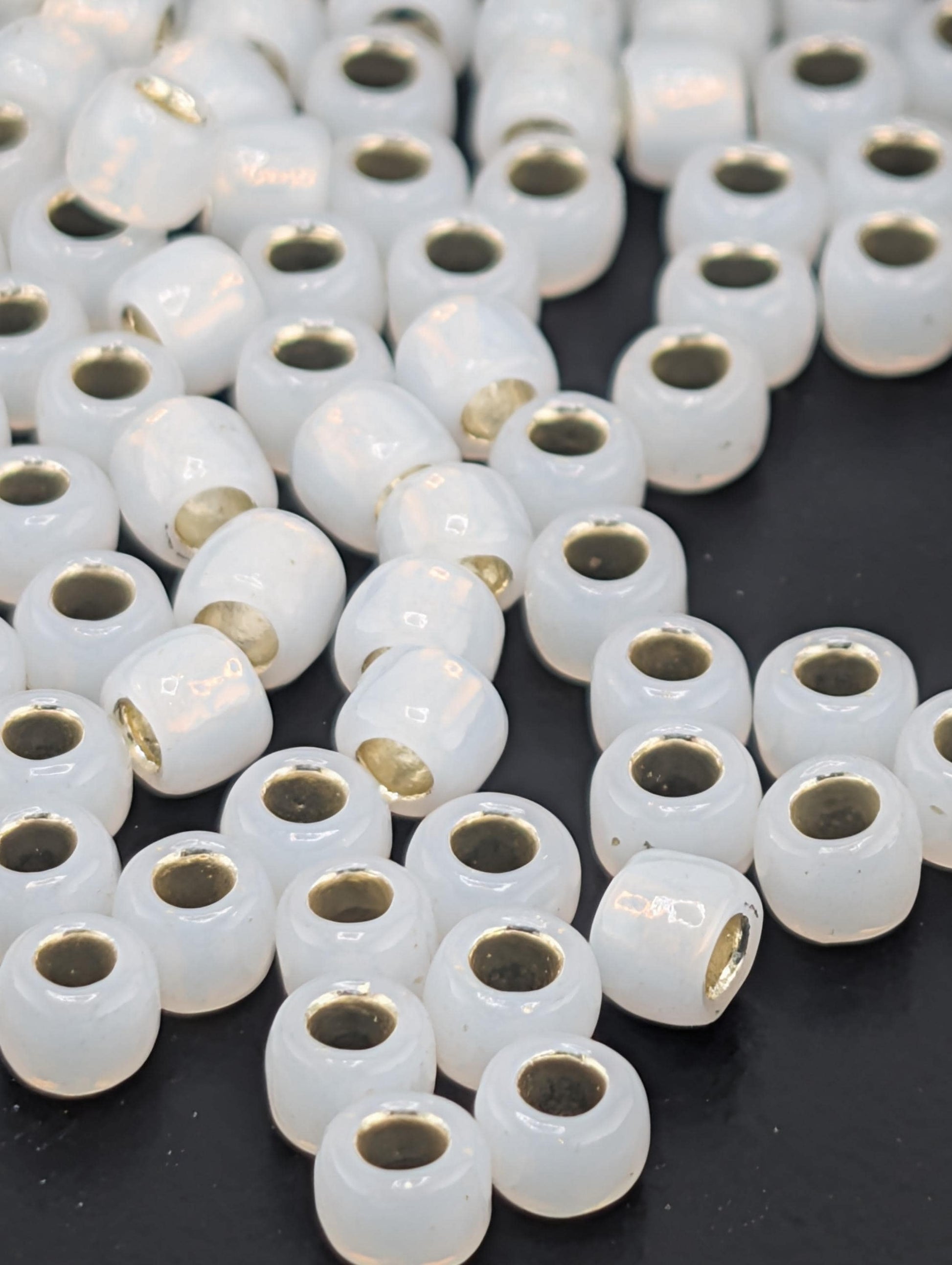 a collection of white, round beads with gold accents scattered across a dark background.