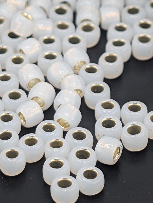 a collection of white, round beads with gold accents scattered across a dark background.