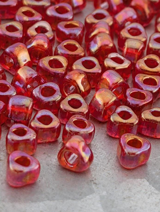 a collection of red and orange glass beads scattered on a surface.