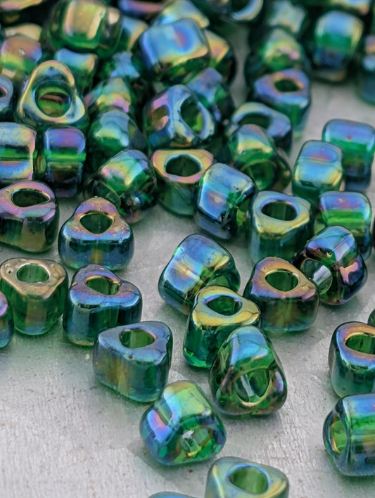 a collection of green glass beads scattered on a surface, with some of the beads overlapping each other.