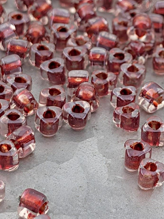 a collection of small, clear beads in various shades of red, scattered across a surface.