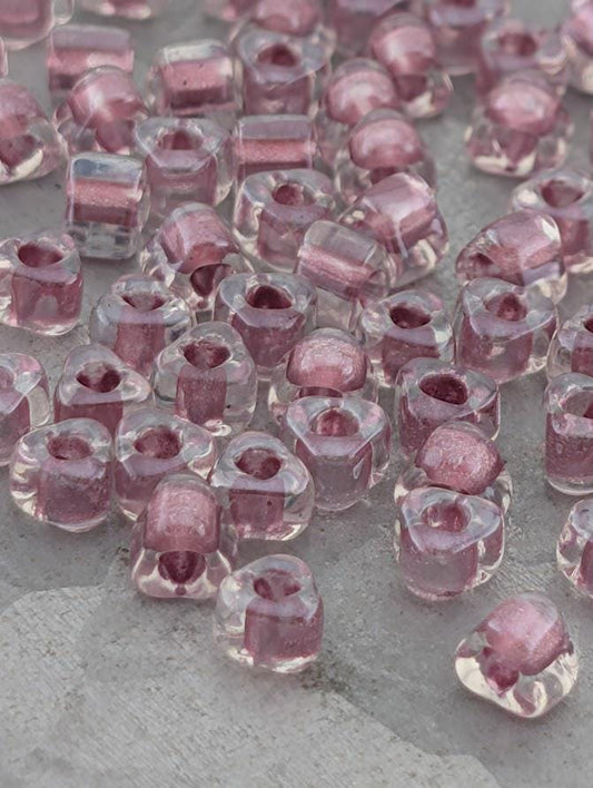 a collection of clear glass beads in various shades of pink, scattered across a surface.