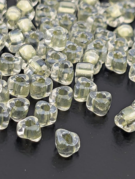 a collection of clear, transparent beads scattered on a dark surface.