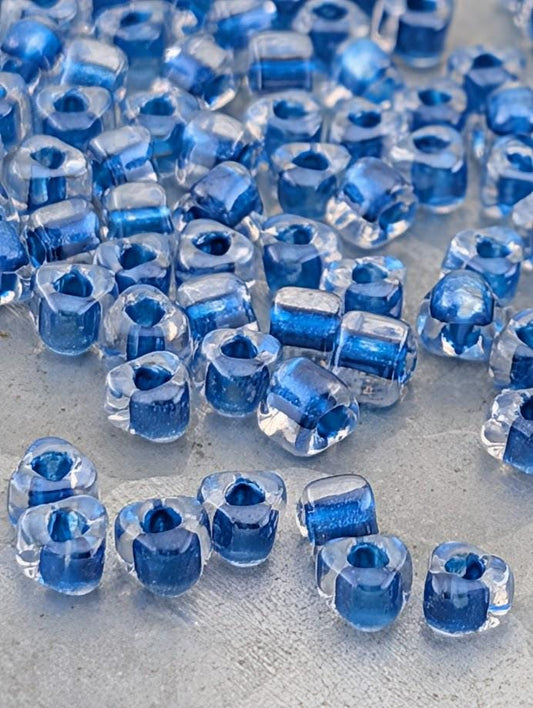 a collection of clear glass beads in various shades of blue, scattered across a surface.