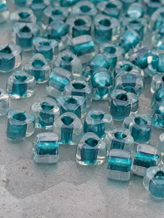 a collection of clear glass beads in various shades of blue, scattered across a surface.