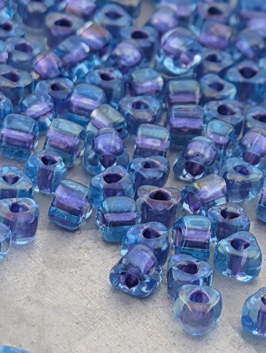 a collection of small, clear glass beads in various shades of blue, scattered across a surface.