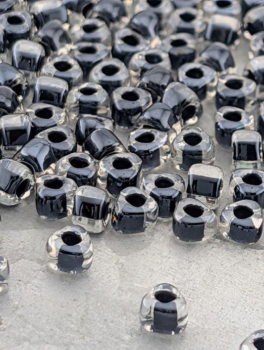 a collection of clear glass beads scattered across a surface, with some of the beads appearing to be black.