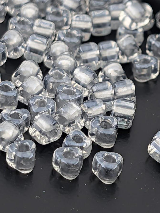 a collection of clear, transparent beads scattered on a dark surface.