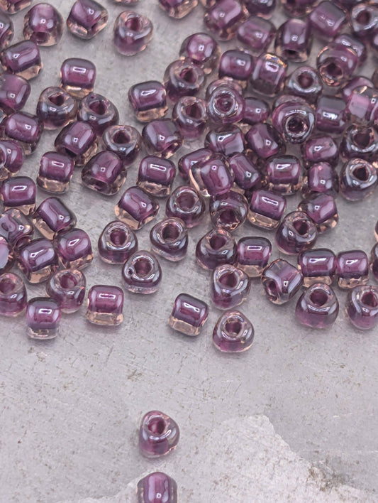 a collection of small, clear beads in various shades of purple scattered across a surface.