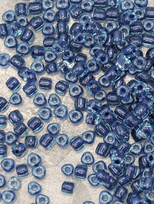 a collection of small, clear beads in various shades of blue, scattered across a surface.