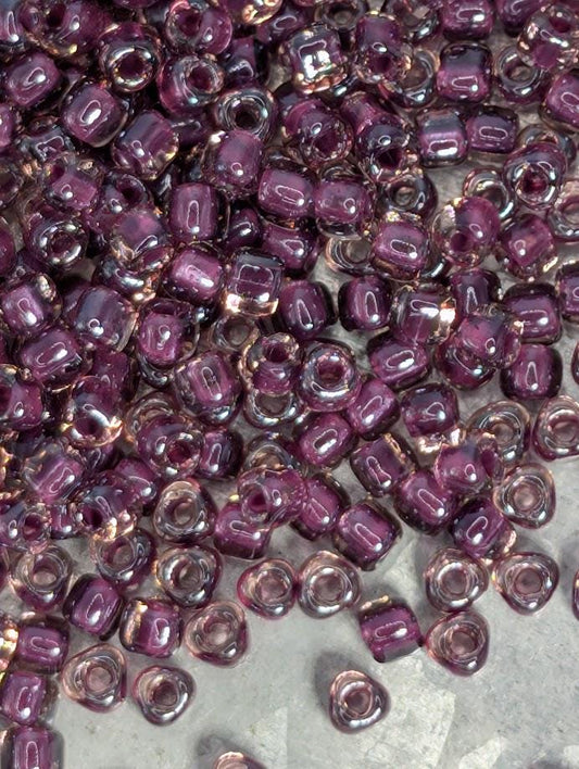 a close-up view of numerous small, clear beads in shades of purple and pink, scattered across a surface.