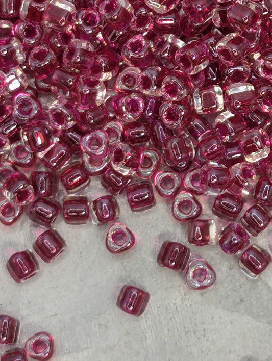 a collection of small, clear beads in shades of pink and purple, scattered across a surface.