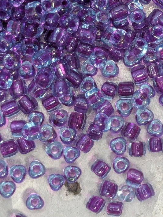 a collection of small, clear beads in various shades of purple, scattered across a surface.