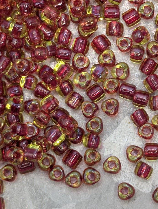 a collection of small, colorful beads in shades of red and yellow, scattered across a surface.