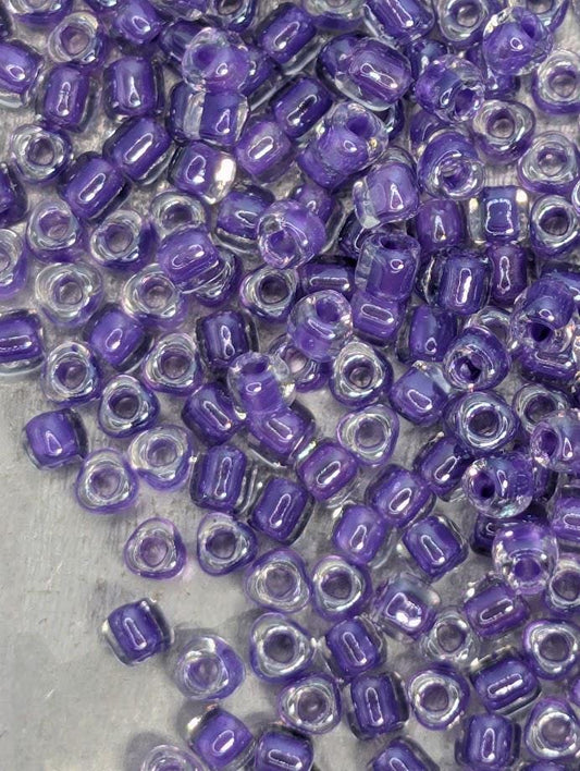 a collection of small, clear beads in shades of purple and white, scattered across a surface.
