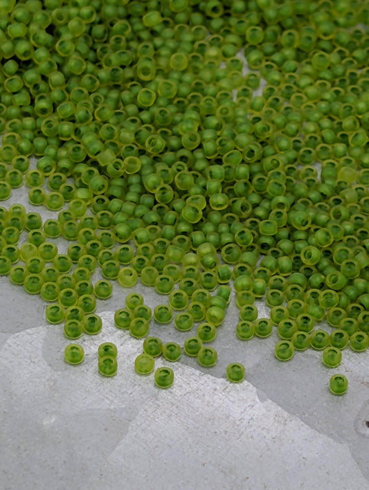 a large pile of green beads or seeds scattered on a white surface.