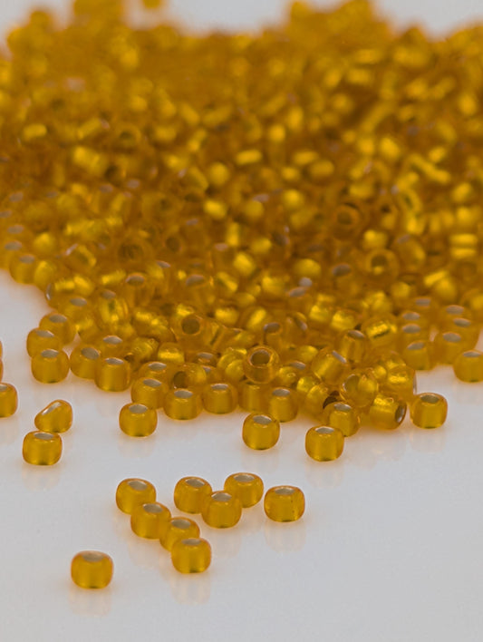 a pile of small, round, yellow beads scattered on a white surface.