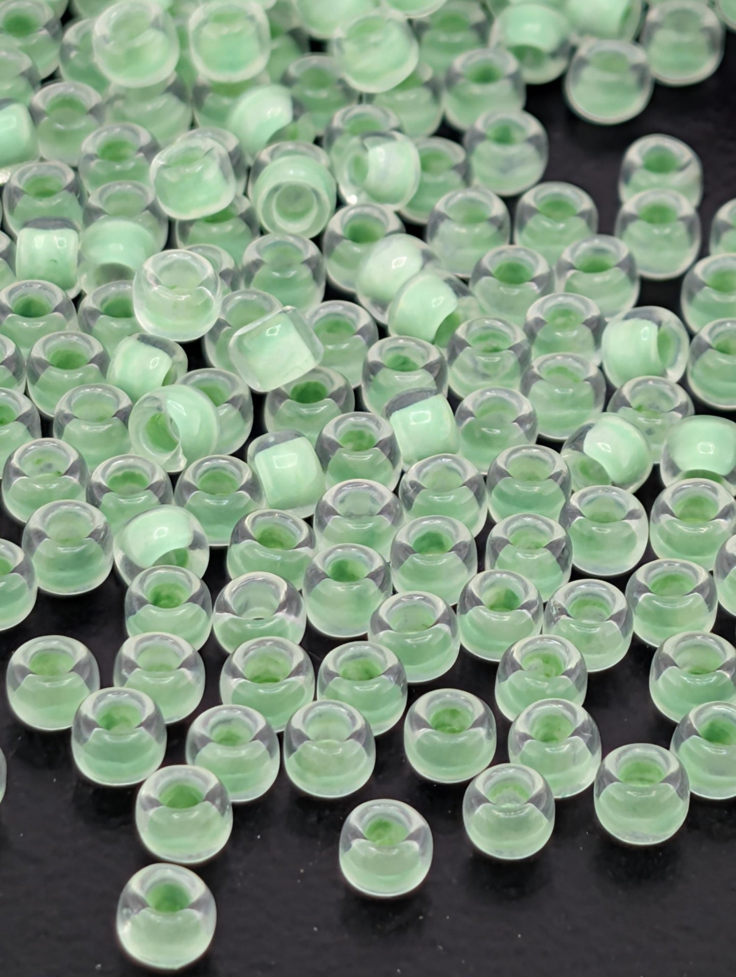 a collection of small, clear glass beads scattered across a dark background.