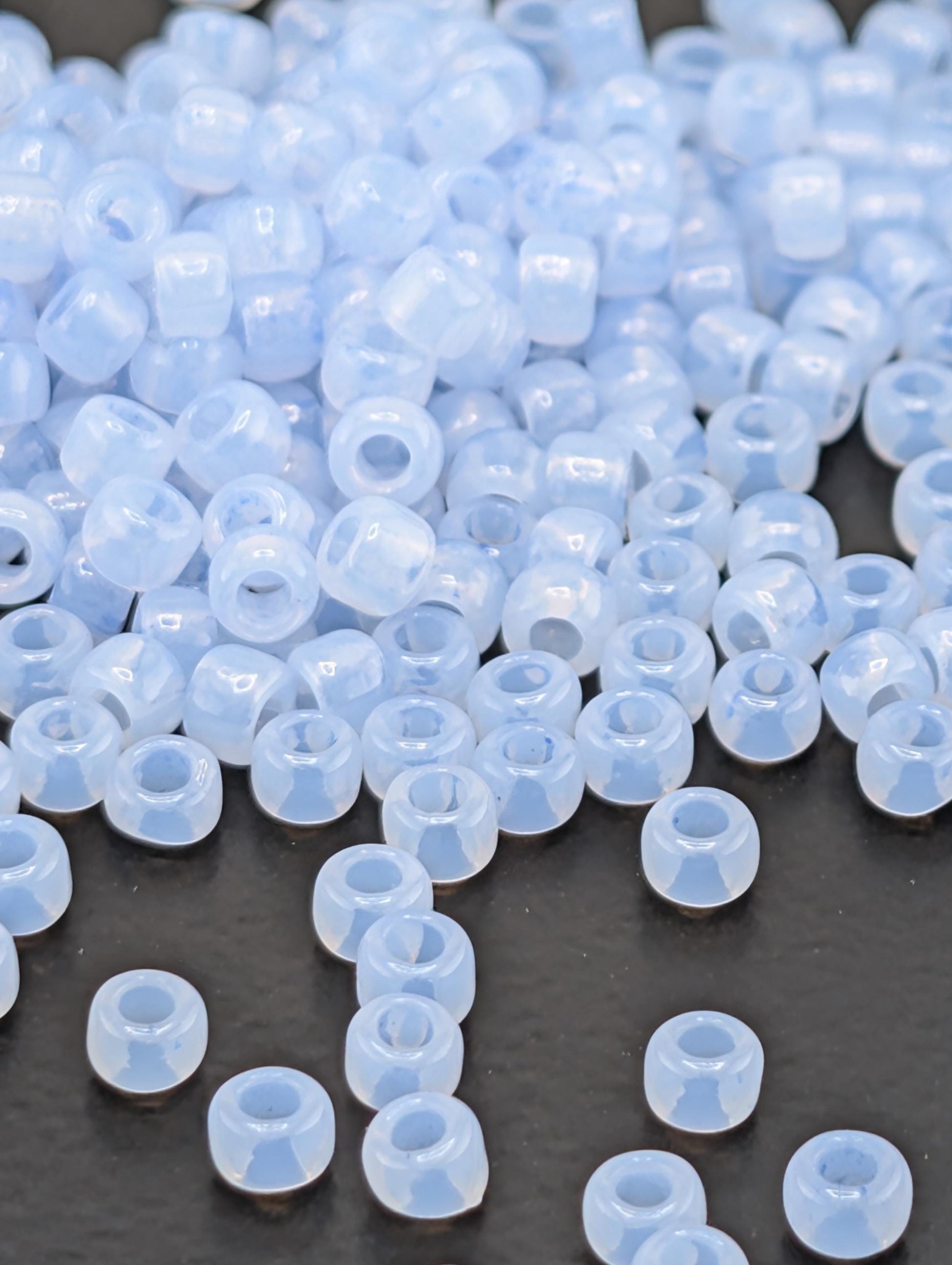 a large pile of clear, translucent beads scattered on a dark surface.